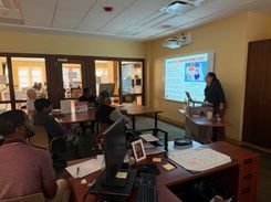 Photo of a computer class in Room 109 taught by instructor Diomaris Gomez, showing participants seated at tables during a lesson on confident internet browsing held on April 14 at 11 p.m., with desktop computers visible around the room.