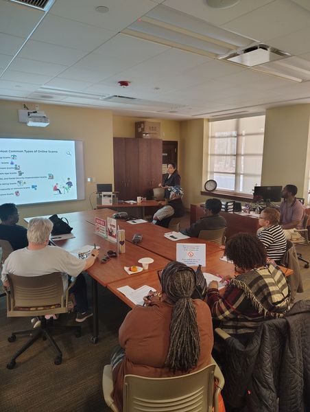 Photo of a computer class in Room 109 taught by instructor Diomaris Gomez, showing participants seated at tables during a lesson on confident internet browsing held on April 14 at 11 p.m., with desktop computers visible around the room.