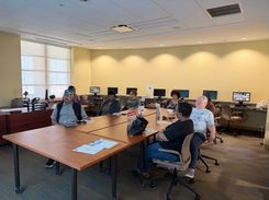 Photo of a computer class in Room 109 taught by instructor Diomaris Gomez, showing participants seated at tables during a lesson on confident internet browsing held on April 14 at 11 p.m., with desktop computers visible around the room.