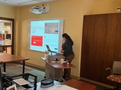 Photo of a computer class in Room 109 taught by instructor Diomaris Gomez, showing participants seated at tables during a lesson on confident internet browsing held on April 14 at 11 p.m., with desktop computers visible around the room.