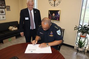 Akers signing document, Earl Bonett observing